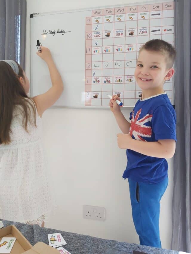 Whiteboard with weekly schedule, children studying and writing, The Study Buddy website branding, educational environment, colourful icons and writing, focus on learning and organisation.
