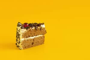 Chocolate and vanilla layered cake slice with sprinkles and cherry on top against a bright yellow background, showcasing The Study Buddy website's focus on engaging and colourful educational content.
