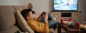 An image of a teen playing video games, lounging about. Not studying.